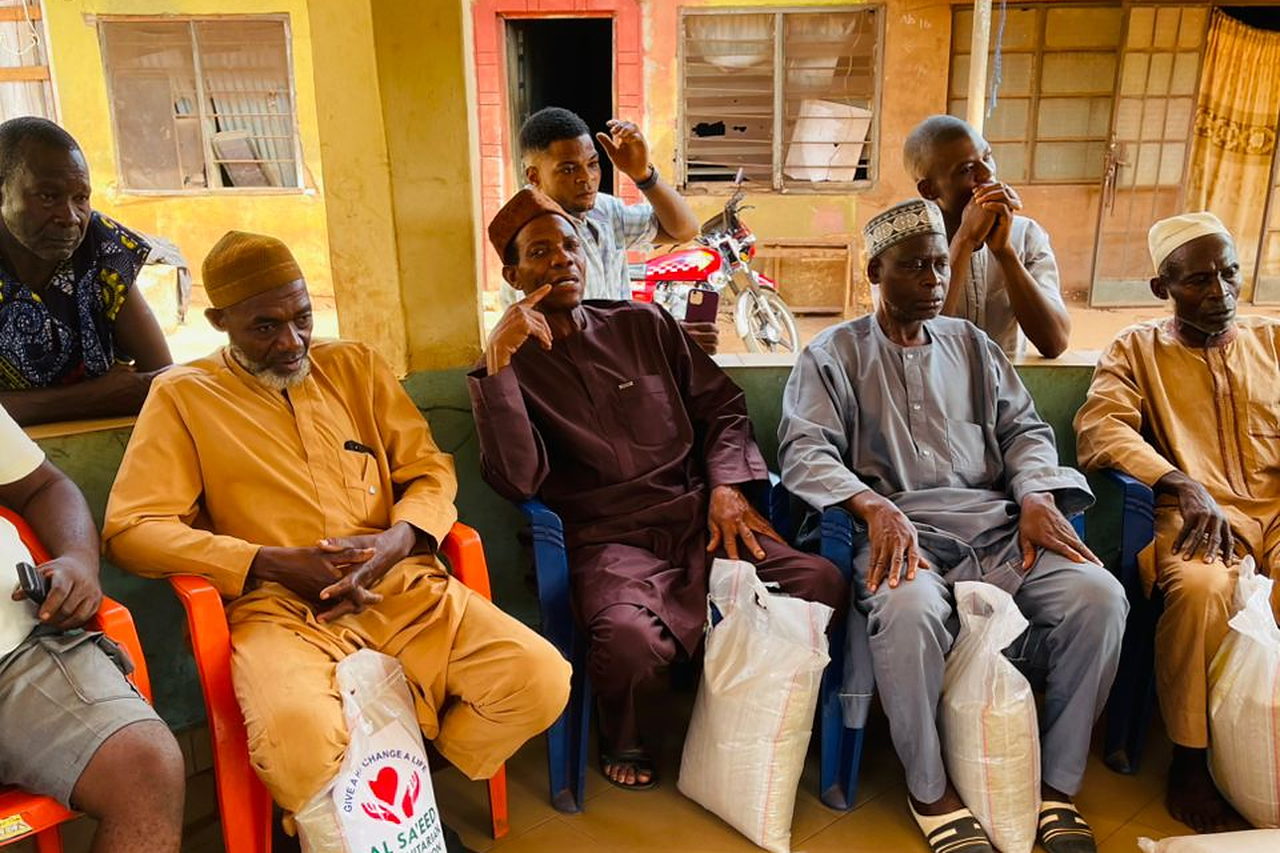 Older men seated with bags of food supplies received from Al Sa'eed Humanitarian Foundation.
