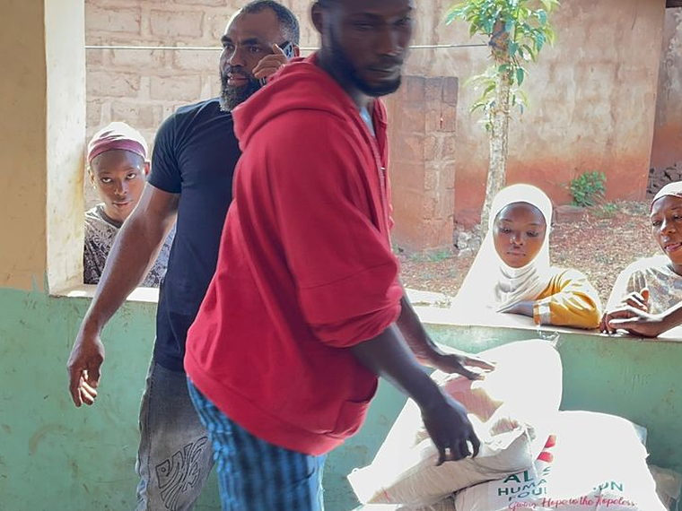 A volunteer moving sacks of food supplies branded with the Al Sa'eed Humanitarian Foundation logo.